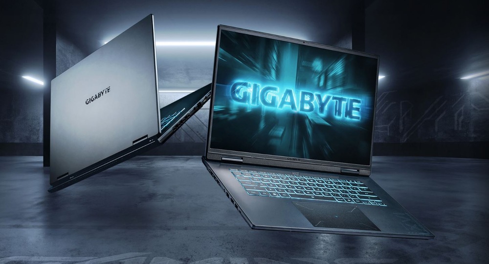 V temné místnosti se vznáší dva elegantní notebooky s modrým nápisem Gigabyte. Zářivá atmosféra navozuje dojem high-tech a futuristického prostředí.