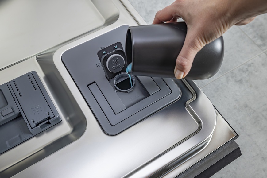 Myčka nádobí Hisense HV693A66UVAD Detailní záběr na zásobník pro detergent o objemu 0,5 litru. Paní do něj doplňuje mycí prostředek.