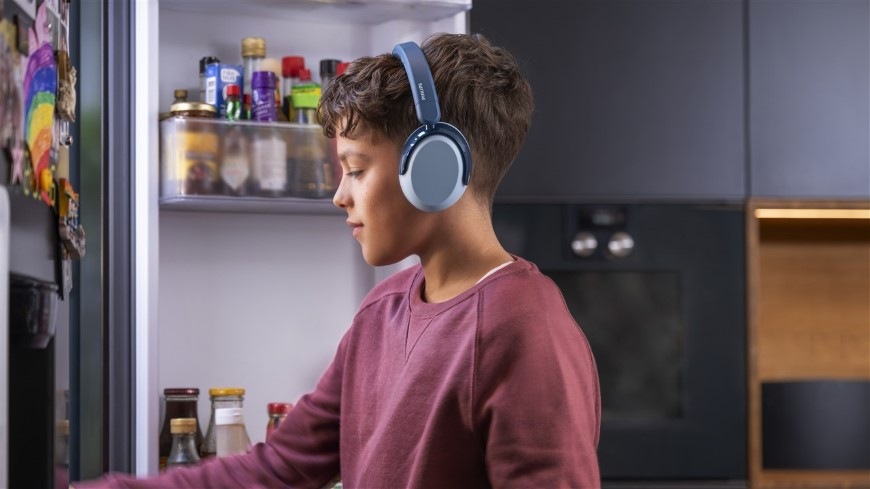 Sluchátka Philips Dětská TAK5500RT modrá Chlapec se sluchátky Philips TAK5500AL sahá do ledničky pro jídlo