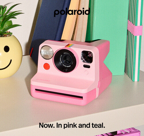 Instantní fotoaparát Polaroid Now Gen 3 růžový Růžový instantní fotoaparát Polaroid Now Gen 3 položený na stole vedle knih a dekorací v moderním interiéru