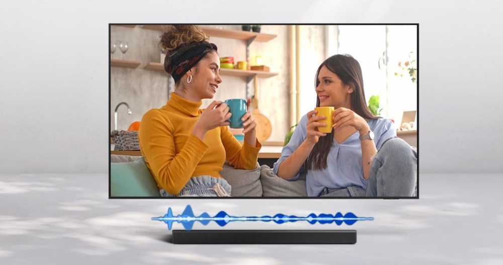 Soundbar Samsung HW-Q930H černý televize Samsung, na které je zobrazeny dialog dvou žen. Pod TV je soundbar. Díky režimu Active Voice Amplifier se zvýší hlasitost řeči, aby lepe vynikla