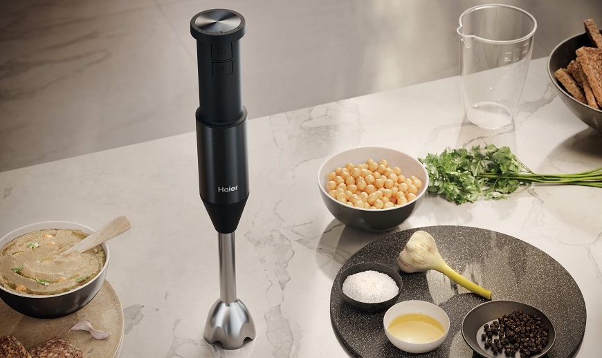 Ponorný mixér Haier HHB5B2/1 011 na stole v kuchyni, vedle něj jsou různé ingredience