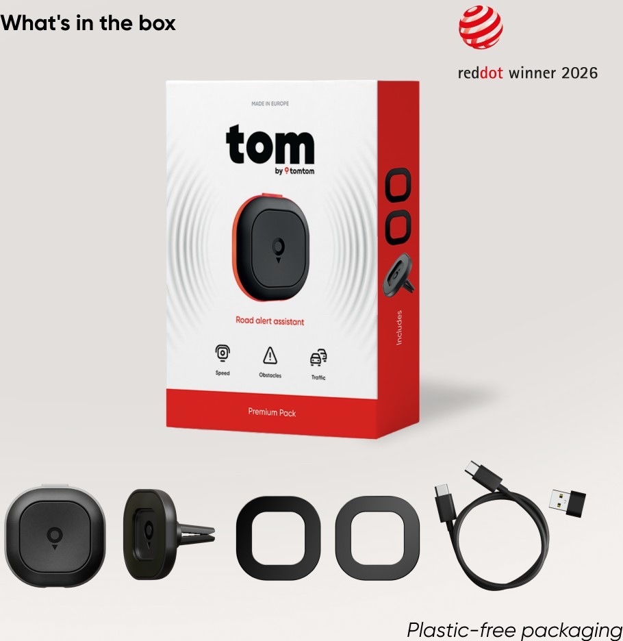 Balení TomTom Tom Premium Pack s cestovním asistentem, držákem do ventilační mřížky, dvěma adhezivními držáky, nabíjecím kabelem USB-C a redukcí USB-A. Vpravo nahoře je označení Red Dot Winner 2026.