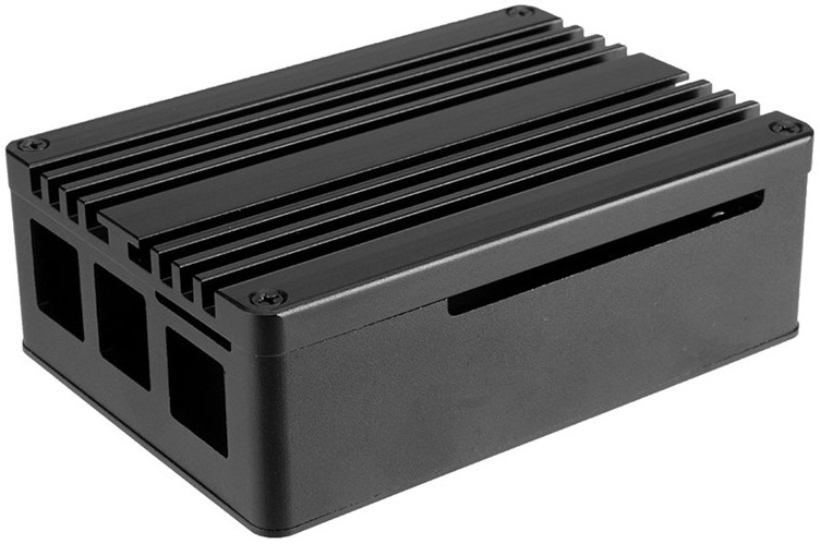 Case AKASA Pi 4 Pro Extended Aluminium case with Thermal Modules for Raspberry Pi 4 Model B černá Na snímku je vidět čelní a levá strana pouzdra v černém pískovaném eloxovaném hliníku. V popředí vynikají obdélníkové výřezy pro porty Raspberry Pi (USB, HDMI, Ethernet atd.), které jsou přesně zarovnané s hranou pouzdra. Nad těmito výřezy je dobře patrný malý otevřený přístup k microSD slotu, který je částečně zakrytý konstrukcí pouzdra, ale stále dobře přístupný.