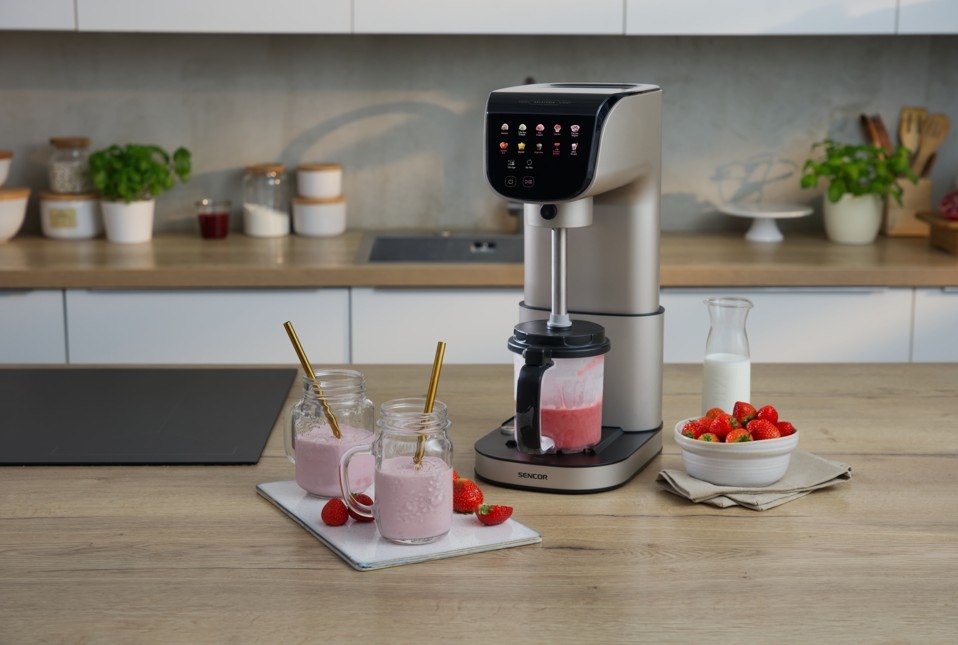 Zmrzlinovač Sencor SIC 5050WS GELATERIA champagne Zmrzlinovač Sencor SIC 5050WS GELATERIA připravuje jahodový milkshake v moderní kuchyni. Vedle přístroje stojí sklenice s hotovým nápojem doplněné brčky, čerstvé jahody a karafa s mlékem.