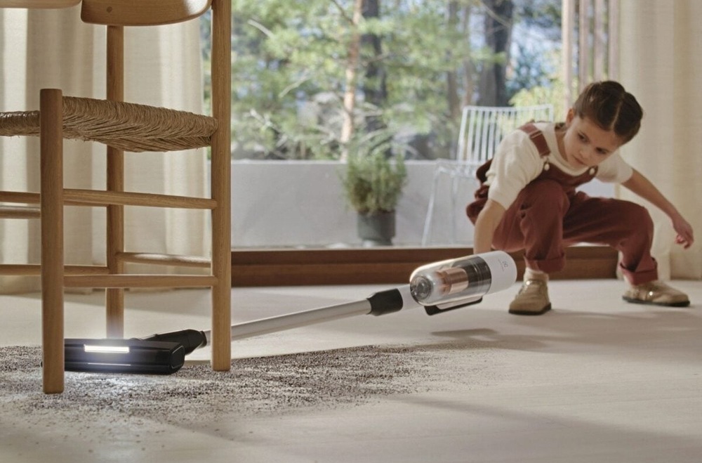 Holčička vysává nepořádek pod židlí s vysavačem Electrolux.