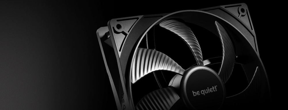  Detailní záběr na elegantní černý počítačový chladicí ventilátor na tmavém pozadí. Lopatky mají kovový lesk a na náboji je viditelné logo výrobce be quiet!.