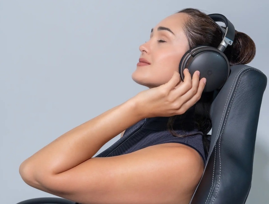 Headset Audeze Maxwell 2 ANC - Xbox černý Žena odpočívající v křesle s nasazeným headsetem Audeze Maxwell 2 ANC v lifestylovém záběru