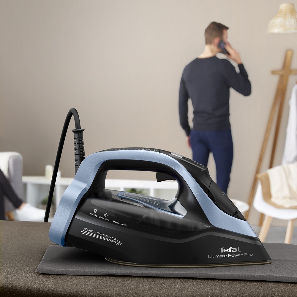 Žehlička Tefal Ultimate Power Pro FV9E53E0 černá/modrá Muž telefonuje a na žehlicím prkně nechá položenou žehličku Tefal FV9E53E0 Ultimate Power Pro, která se sama vypne