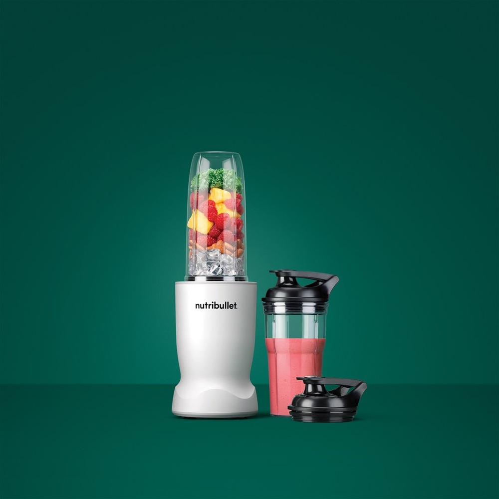 Mixér NutriBullet černý s přenosným kelímkem s růžovým smoothie na zeleném pozadí.