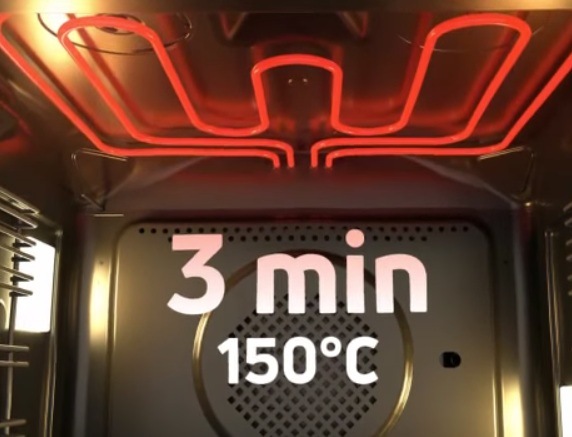 Trouba Amica ED37610X X-TYPE nerez Rozehřáté topné těleso uvnitř trouby. Přes mřížku ventilátoru je nápis 3 minuty a 150 °C.