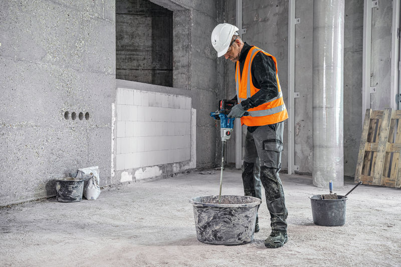 Míchadlo Bosch Professional GRW 18V-160 (bez baterie) Pohled na muže na stavbě, který v rukou drží míchadlo Bosch Professional GRW 18V-160 a míchá v kbelíku cement.