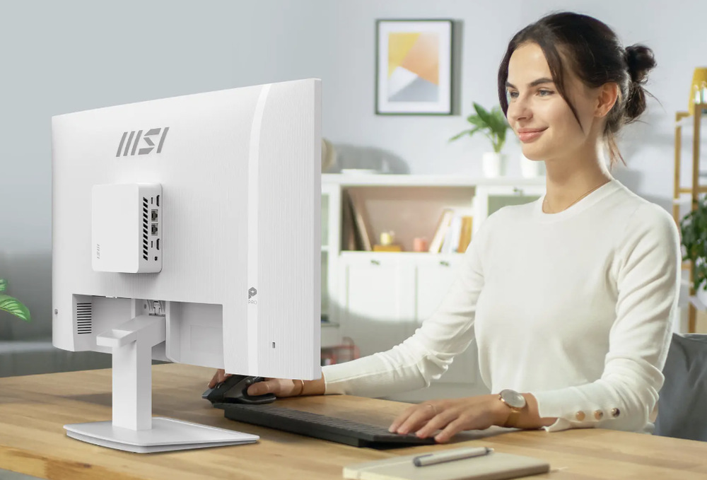 Žena pracuje u monitoru MSI PRO MP273W E14A s mini PC upevněným na jeho zadní straně