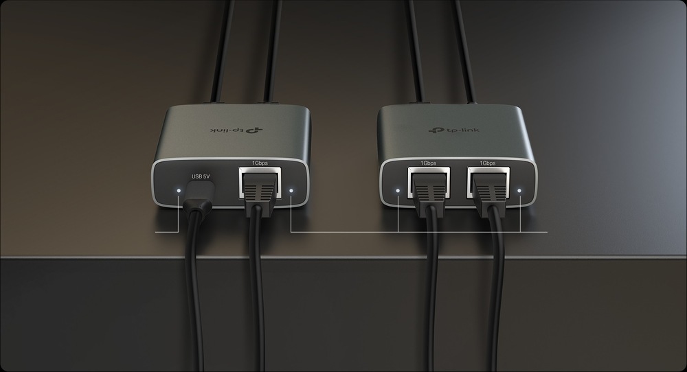 Dva elegantní kovové síťové adaptéry s logem TP-Link leží na tmavém povrchu. Každý adaptér má ethernetové kabely zapojené do portů 10 Gb/s, které zajišťují moderní připojení.