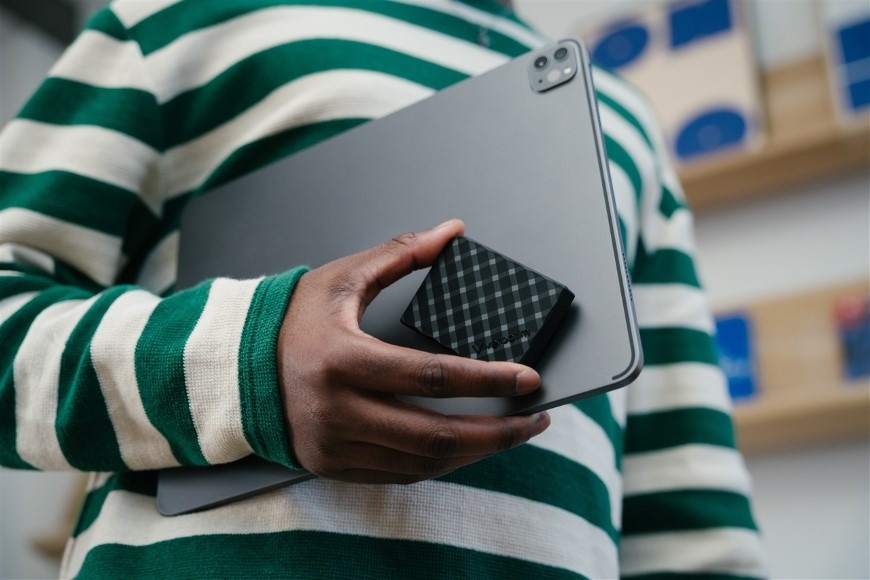 Detail osoby nesoucí v jedné ruce notebook a kompaktní SSD Verbatim Store 'n' Go Mini Diamond