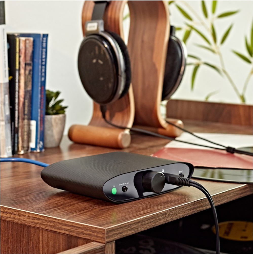 Sluchátkový zesilovač iFi audio ZEN Air DAC černý Sluchátkový zesilovač iFi Audio ZEN Air DAC na dřevěném stole, připojený ke sluchátkům, s velkým ovladačem hlasitosti na čelním panelu.