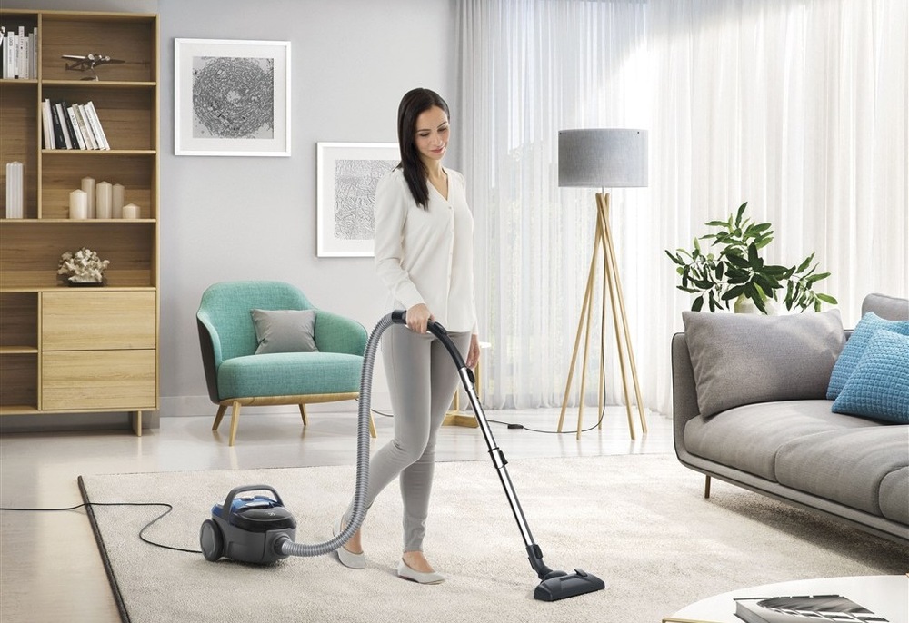 Podlahový vysavač Electrolux CompactGo Cyclonic ECGC21-2CB modrý Žena vysává vysavačem Electrolux ECGC21-2CB CompactGo Cyclonic koberec v obýváku.