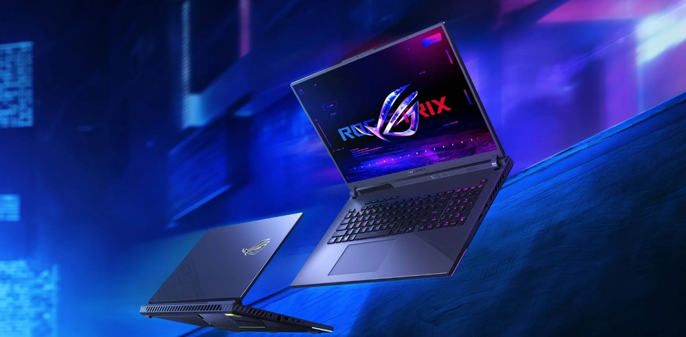 Dva herní notebooky jsou vystaveny na modrém a fialovém futuristickém pozadí. Jeden je otevřený a na jeho zářivém displeji je nápis ROG STRIX.