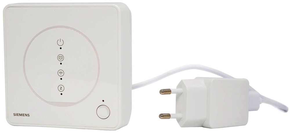 Bílá centrální jednotka Siemens Connected Home vedle napájecího adaptéru do zásuvky. Na přední straně jednotky jsou stavové ikony s kontrolkami, logo Siemens a kulaté tlačítko vpravo dole.