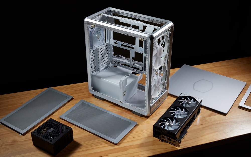 Case Cooler Master MasterFrame 500 Mesh stříbrná Na snímku je otevřená skříň s komponenty, rozloženými na desce stolu. ventilátory, napájení...