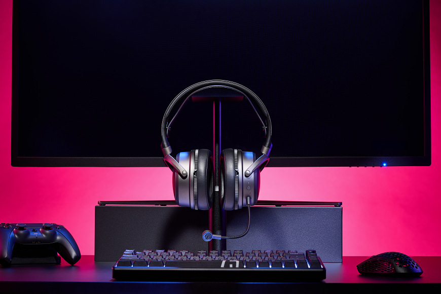 Headset na stojanu před monitorem s herním příslušenstvím