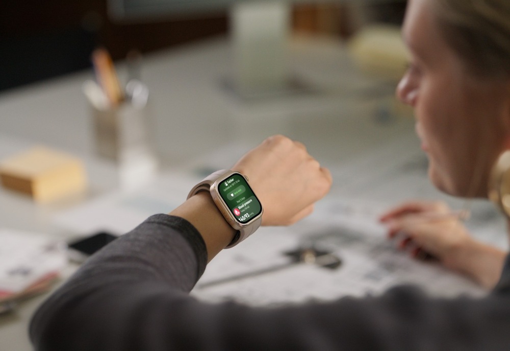 Chytré hodinky Huawei Watch D3 zlaté Žena u pracovního stolu sleduje chytré hodinky na zápěstí, jejichž displej zobrazuje přehled krevního tlaku s naměřenou hodnotou