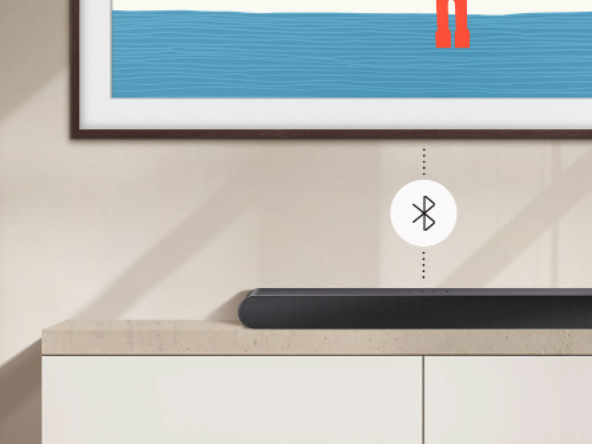 Soundbar Samsung HW-S50B černý Soundbar Samsung leží na skříňce pod televizí Samsung, mezi nimi je kolečko s logem Bluetooth přípojen, obě zařízení jsoiu spojena tečkovanou linkou