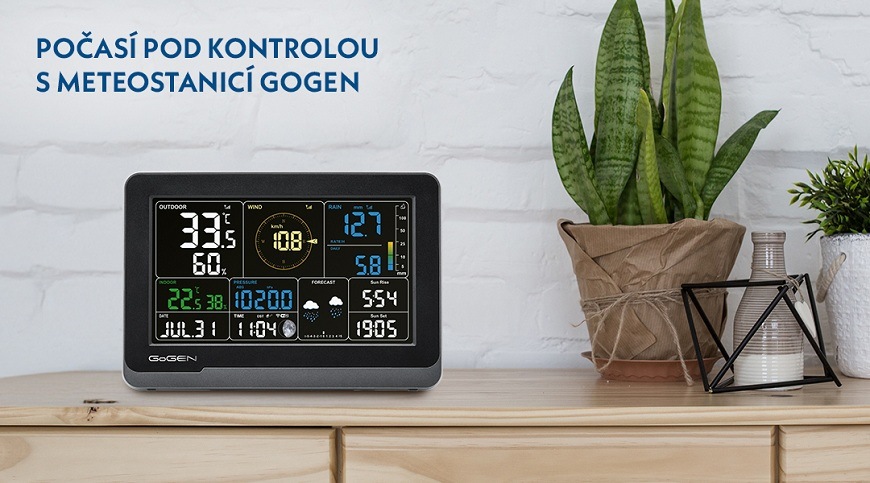 Černá meteostanice GoGEN ME 4900 zobrazující informace o počasí na dřevěné komdě vedle pokojové květiny