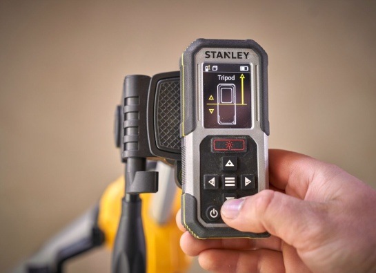 Laserový dálkoměr Stanley v ruce s aktivním režimem měření ze stativu.