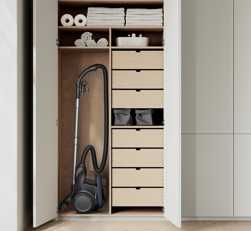 Vysavač Electrolux EL6EL61C3DB série 600 Clean ve svislé poloze v otevřené skříni. Kolem jsou šuplíky a police.