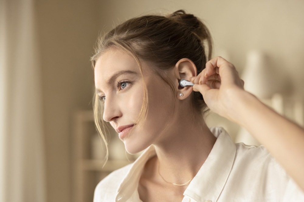Sluchátka Shokz OpenDots 2, Bluetooth šedá Žena se dotýká sluchátek se snadným dotykovým ovládáním