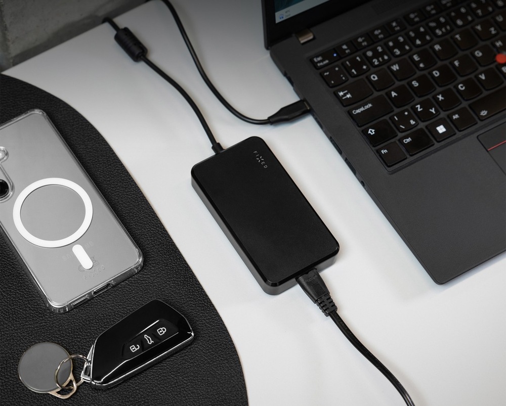 Napájecí adaptér FIXED GaN USB-C, PD 3.0, 100 W černý Nabíjecí adaptér FIXED GaN USB-C, PD 3.0, 100 W vedle notebooku a telefonu