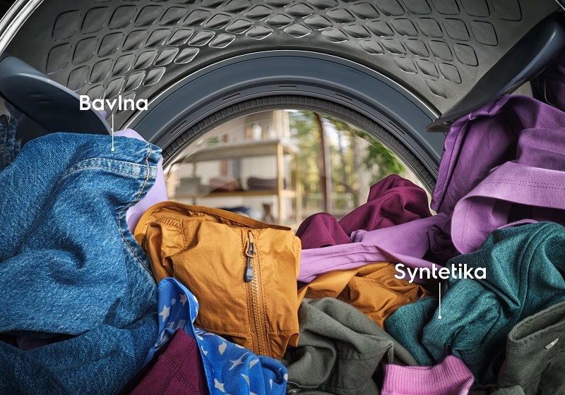 Buben pračky plný barevného oblečení z bavlny a syntetiky.