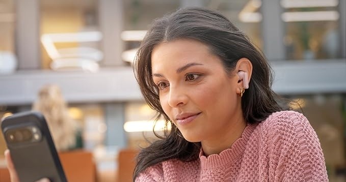 Sluchátka Philips TAT2100LB/00 světle modrá Žena sledující obrazovku telefonu má v uších sluchátka Philips s vestavěnými mikrofony