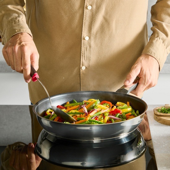 Muž vařící zeleninu na univerzální pánvi Tefal E3270444 Emotion+ 24 cm.
