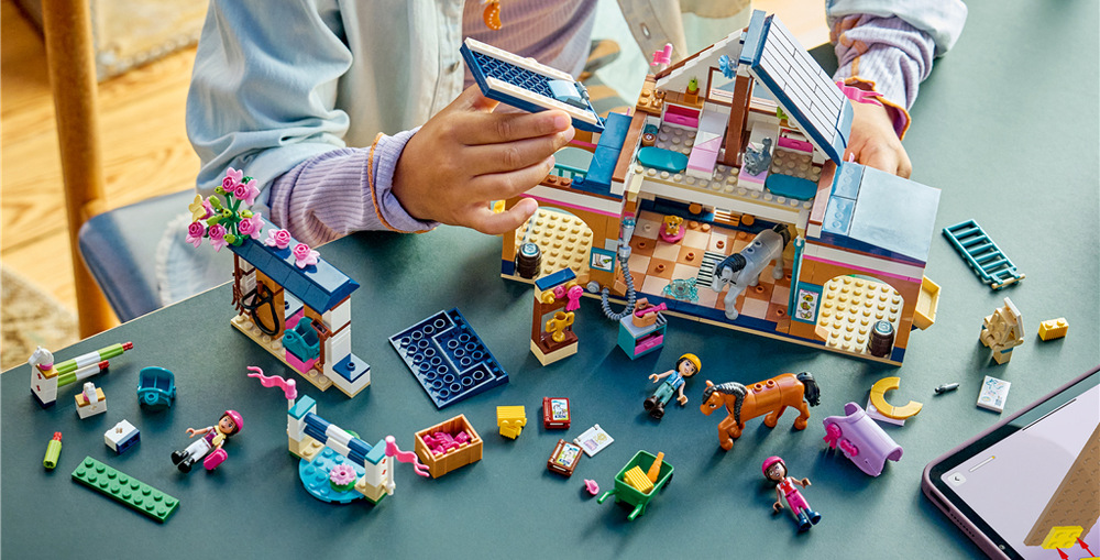 Stavebnice LEGO® Friends 42688 Koňská stáj a jezdecká akademie Před jízdou děti koně nakrmí senem a mrkví, upraví jim srst a připraví sedla i další jezdecké vybavení.