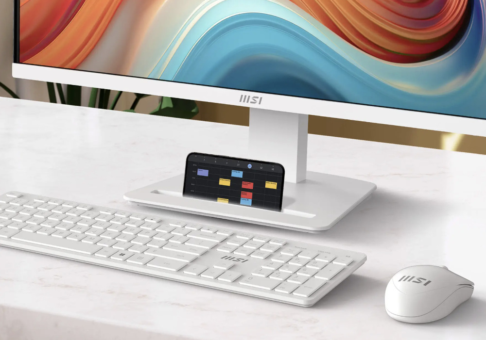 Telefon umístěný ve slotu v základně stojanu monitoru MSI PRO MP273W E14A vedle klávesnice a myši