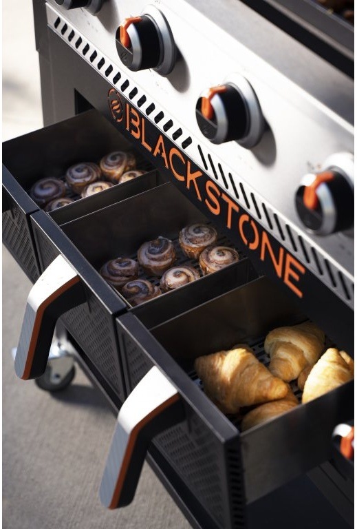 Otevřené zásuvky na pečení grilu Blackstone s skořicovými rolkami a croissanty.
