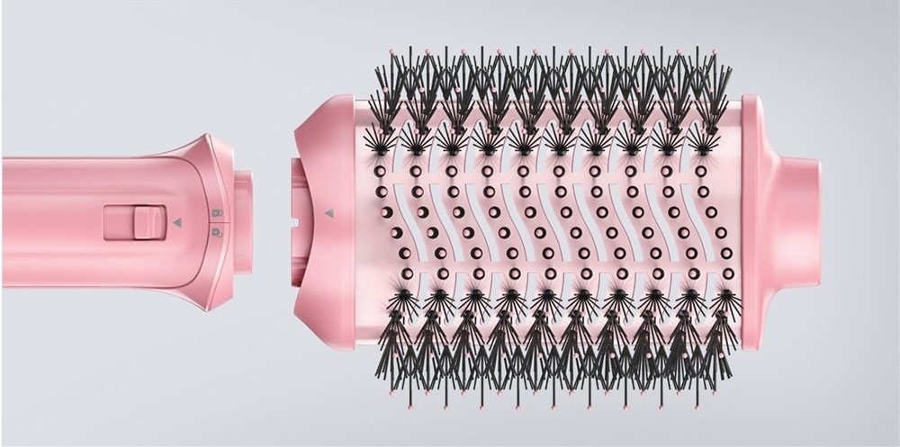 Detail růžového oválného kartáčového nástavce Revlon One-Step Volumiser Glow s hustými černými štětinami, zobrazeného vedle rukojeti před jejich spojením