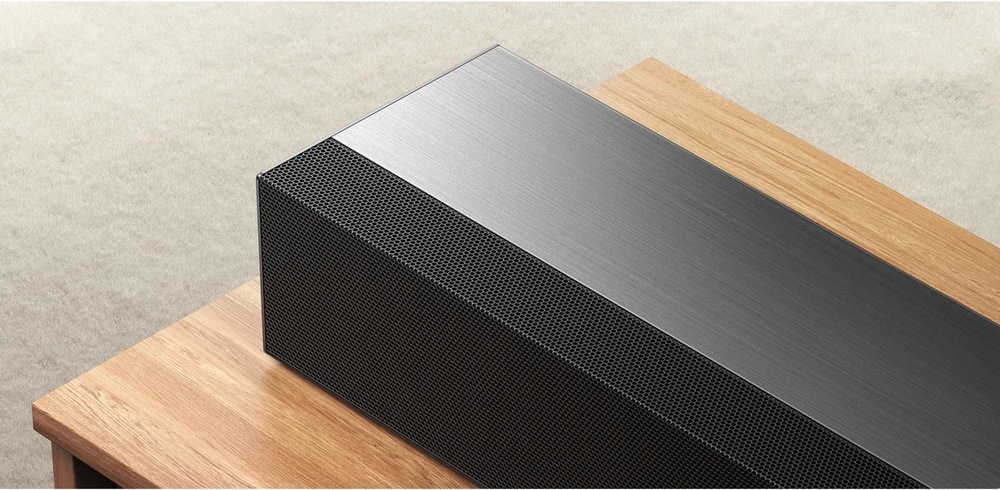 Detail kovové horní plochy soundbaru Xiaomi PRO 2.1 ch položeného na dřevěném TV stolku