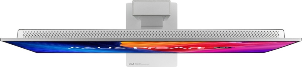 Na obrázku je monitor Asus ProArt OLED PA27UCDMR 27" z horního pohledu. Je vidět velmi tenké tělo displeje, stříbrná zadní část s dlouhou perforovanou větrací mřížkou a uprostřed uchycení ke stojanu. Spodní okraj obrazovky zobrazuje barevnou grafiku ASUS ProArt. Snímek zdůrazňuje štíhlý profil monitoru a čisté profesionální provedení.