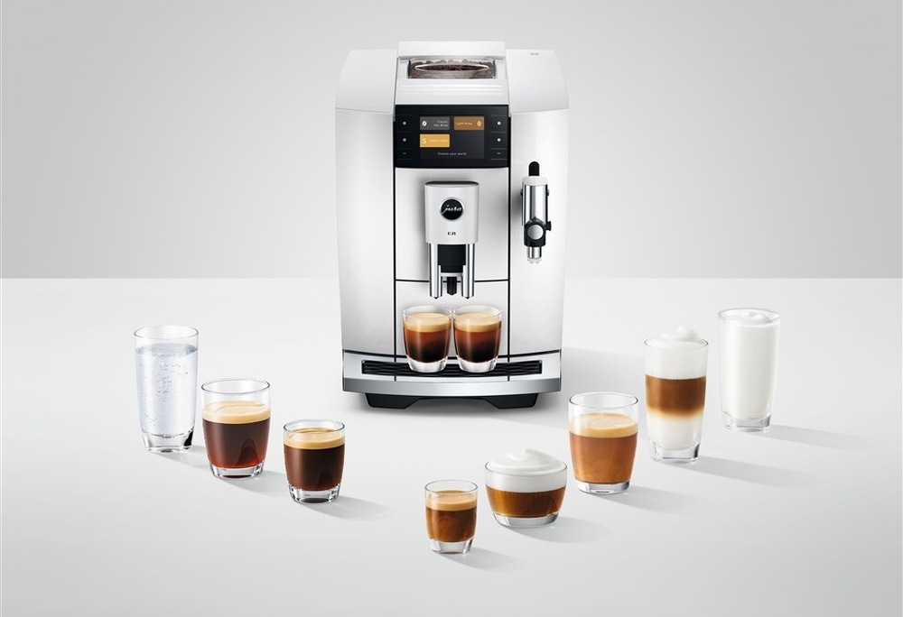 Automatický kávovar Jura E8 Piano White (modelový rok 2026) bílý Automatický kávovar Jura E8 Piano White připravuje dva šálky kávy zároveň, kolem kávovaru je rozestavěno osm sklenic s různými druhy kávy