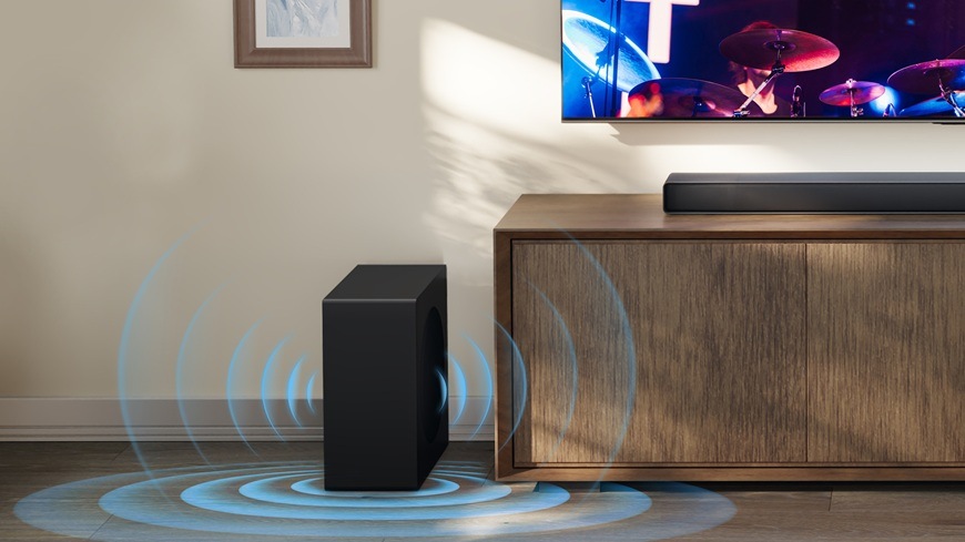 Soundbar Hisense AX3120Q černý Výkonný subwoofer vedle televizního stolku zajišťuje hluboké basy v moderním domácím kině.