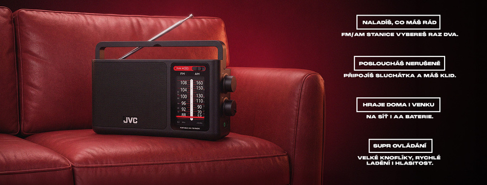 Radiopřijímač JVC RA-E435B černý Produktový banner s černým přenosným rádiem JVC RA-E435B položeno na červené kožené pohovce. Rádio má vysunutou anténu, přehlednou stupnici FM/AM a otočné knoflíky. Vpravo jsou uvedeny klíčové vlastnosti: FM/AM stanice, připojení sluchátek pro nerušený poslech, napájení ze sítě i na AA baterie a snadné ovládání pomocí velkých knoflíků.