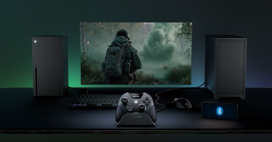 Gamepad SteelSeries Aeon Pro černý Gamepad SteelSeries Aeon Pro v doku před monitorem, mezi Xboxem a počítačem.