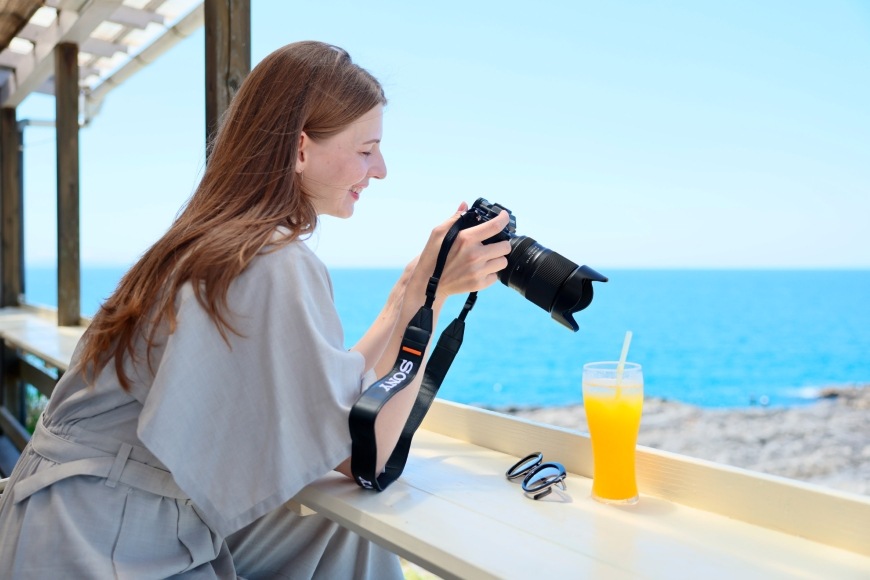 Objektiv Tamron 25-200 mm f/2.8-5.6 Di III VXD G2 (Sony FE) černý Žena se dívá na displej fotoaparátu s nasazeným objektivem Tamron 25–200 mm f/2.8–5.6 Di III VXD G2
