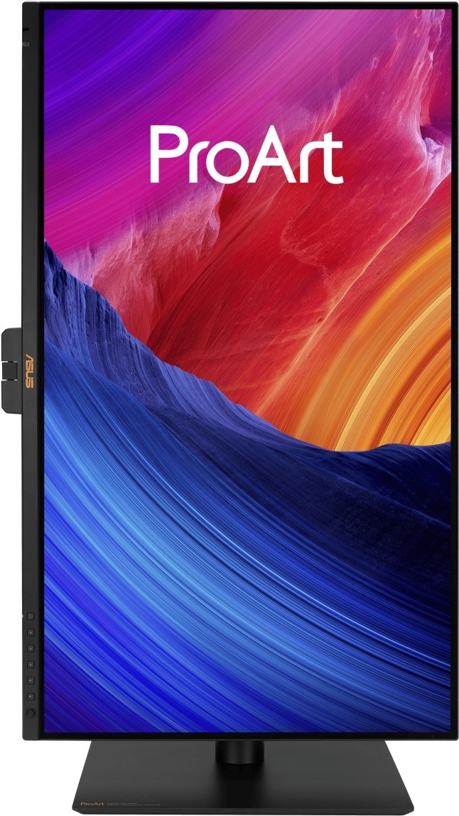Na obrázku je monitor Asus ProArt PA27UCGE 27" otočený na výšku v režimu pivot. Displej stojí na černém stojanu s plochou základnou a zobrazuje barevnou grafiku ProArt v modrých, červených, fialových a oranžových tónech. Na levém spodním rámečku jsou vidět ovládací tlačítka a na levé straně částečně vystupuje uchycení monitoru ke stojanu. Obrázek ukazuje možnost práce s monitorem ve svislé poloze, například pro úpravu fotografií, grafiku nebo delší dokumenty.