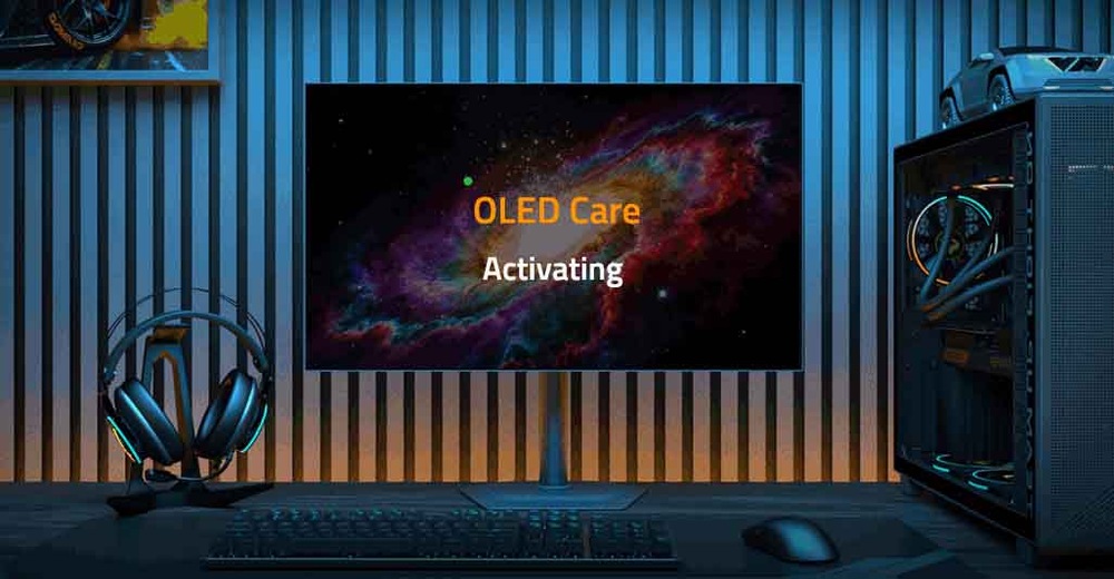 Slabě osvětlená místnost s počítačem. Na obrazovce se na kosmickém pozadí zobrazuje nápis „Funkce OLED Care aktivována“. Sluchátka a herní věž vyzařují jemné modré světlo.
