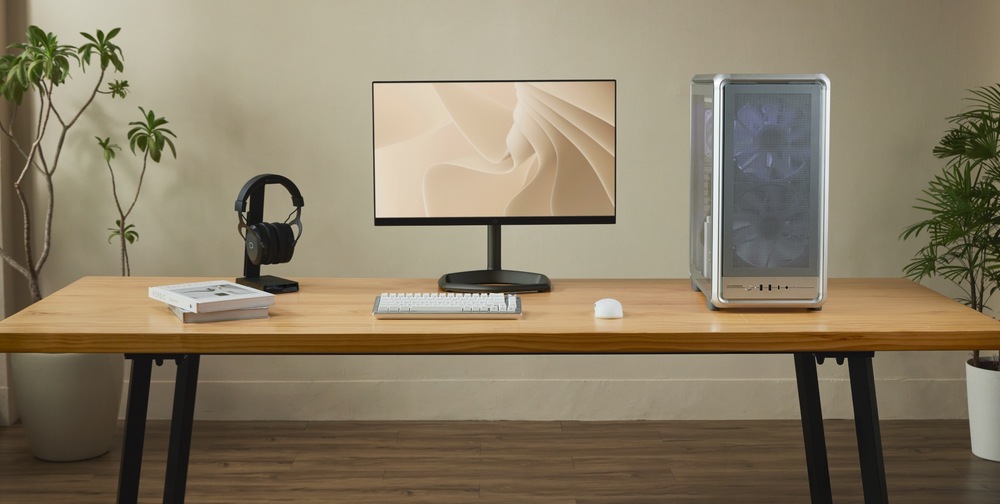 Case Cooler Master MasterFrame 500 Mesh stříbrná Ilustrační foto hotové kompletní sestavy na stole v pracovně. Počítač, klávesnice, myš, monitor. V pozadí květiny, dokreslující interiér.