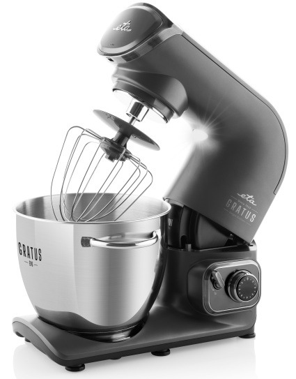 Kuchyňský robot ETA Gratus Evo Origin II s vyklopeným ramenem a nasazenou šlehací metlou nad nerezovou mísou. Snímek prezentuje bezpečnostní systém výkyvného ramene pro snadnou výměnu nástavců, integrované LED osvětlení a elegantní celokovový design přístroje